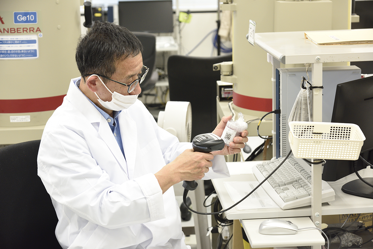 Un membre du personnel scanne un code QR pour enregistrer les informations d’un échantillon au Centre de technologie agricole de Fukushima. | RYOICHI SHIMIZU
